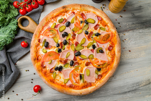 pizza with ham and cucumbers on grey wooden table top view