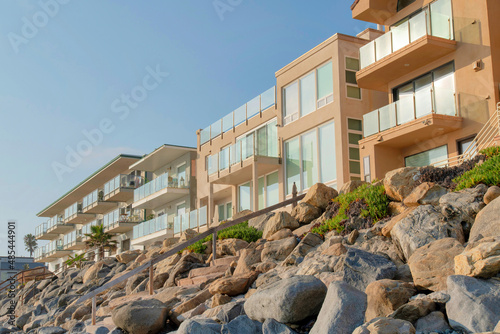 Wall Mural Rocky seawall with wooden handrails near the beachfront buildings at Oceanside,