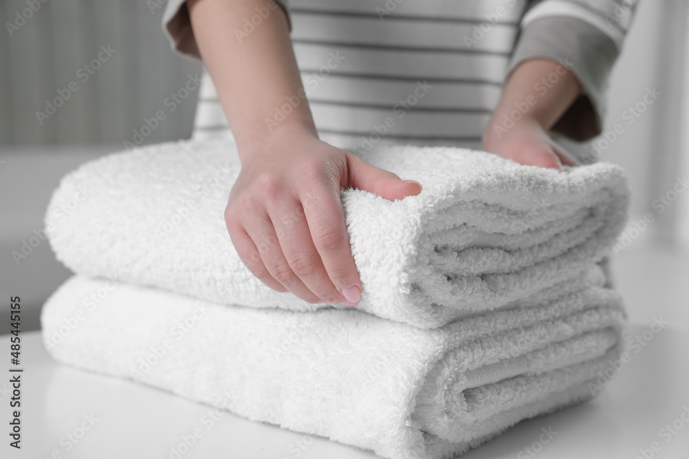 Woman touching soft white towel indoors, closeup