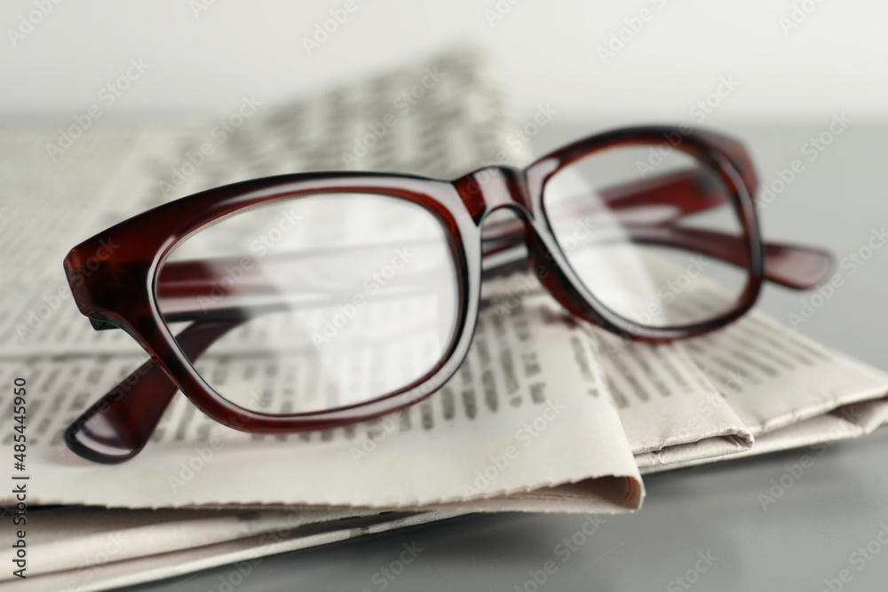 Newspapers and glasses on grey table, closeup Newspapers and glasses on grey table, closeup