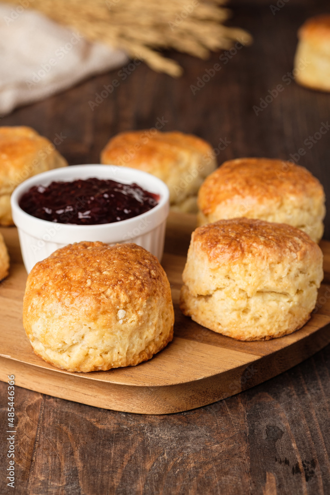 group of scones on wood plate with jam on table