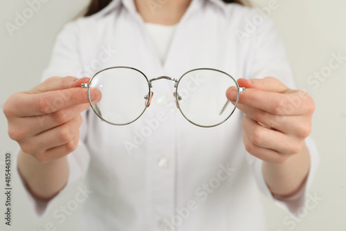 Woman with glasses on light background, closeup