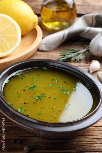 Bowl with lemon sauce on wooden table, closeup. Delicious salad dressing
