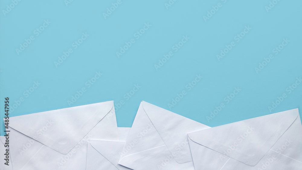 A stack of white envelopes on blue background with copy space. - obrazy, fototapety, plakaty 