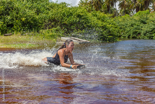 Fototapeta Naklejka Na Ścianę i Meble -  Mulher deslizando numa prancha sob agua num rio