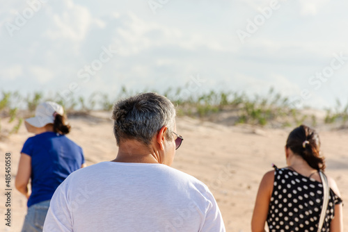 Grupo de pessoas em férias caminhando por dunas de areia © Rogerio