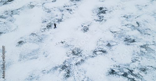 Aerial view from above on one person walks among an icy lake in winter