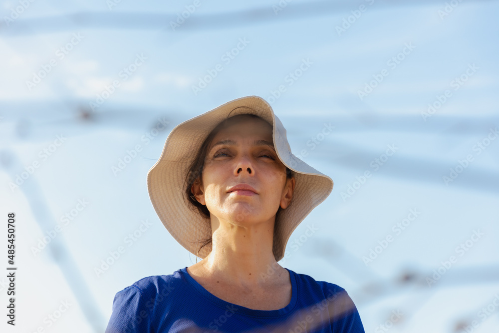 Mulher estilosa de chapéu branco com céu azul