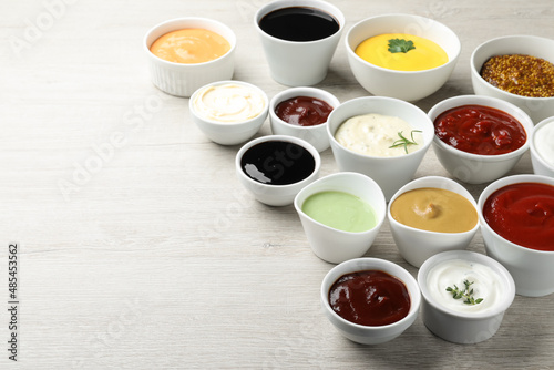 Many different sauces on white wooden table, space for text