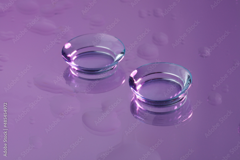 Pair of contact lenses on wet violet reflective surface Pair of contact lenses on wet violet reflective surface