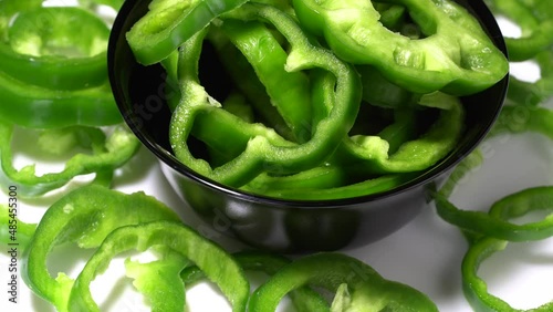 Sliced green bell peppers in a black bowl rotation