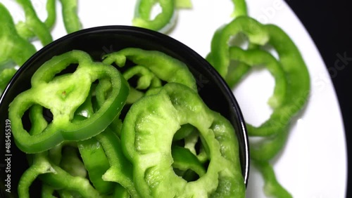 Sliced green bell peppers in a black bowl rotation