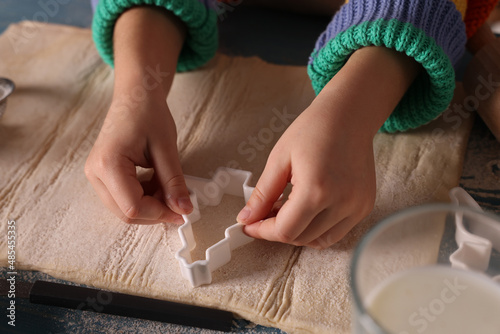 Little child cutting Christmas cookies at blue wooden table  closeup