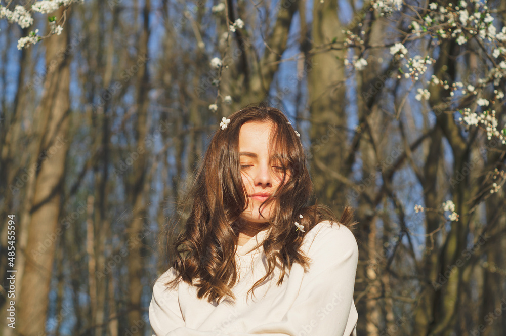 Portrait of young beautiful woman among flowering trees. A woman rejoices in spring flowers. Breathe free. Happy woman no allergies. Spring allergy concept. Fashion and beauty. Spring concept Portrait of young beautiful woman among flowering trees. A woman rejoices in spring flowers. Breathe free. Happy woman no allergies. Spring allergy concept. Fashion and beauty. Spring concept