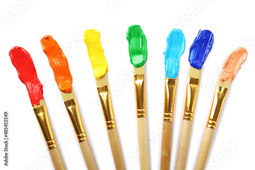 Brushes with colorful paints and strokes on white background, top view