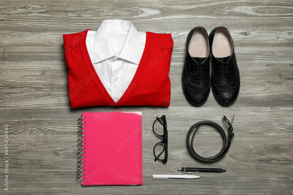 Stylish school uniform for girl, glasses and stationery on wooden background, flat lay Stylish school uniform for girl, glasses and stationery on wooden background, flat lay
