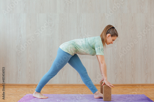 Young caucasian woman doing yoga asanas with yoga bricks at home.