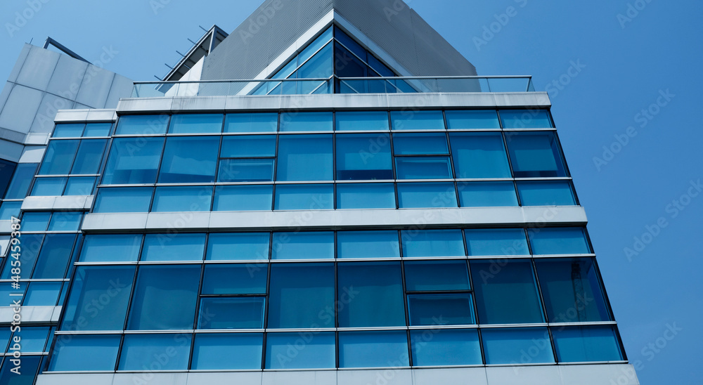 Obraz premium business building in city with mirror windows with reflections of blue sky.