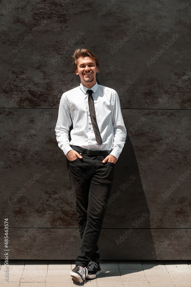 Portrait of startup businessman in a white shirt with a black tie standing in front of gray wall outside Portrait of startup businessman in a white shirt with a black tie standing in front of gray wall outside