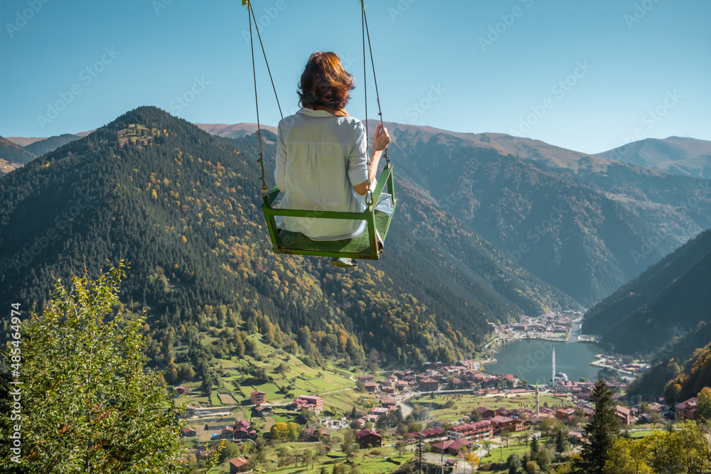 Young woman on a swing with the view of the Uzungol resort town, Turkey