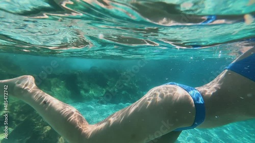 Womans legs underwater in the sea closeup. Blue background with the bubbles and corals.2.7k