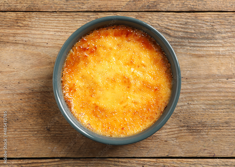 Delicious creme brulee in ceramic ramekin on wooden table, top view