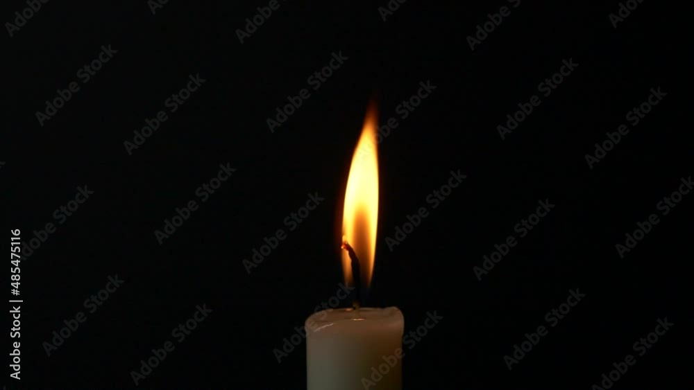 Close-up burning single candle flame isolated on black background, 4K video Close-up burning single candle flame isolated on black background, 4K video