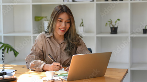 Female college student doing her online assignment on her laptop photo