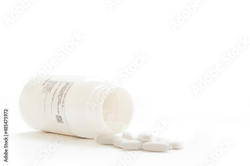 Closeup of a white pills and bottle, on white background with copy space