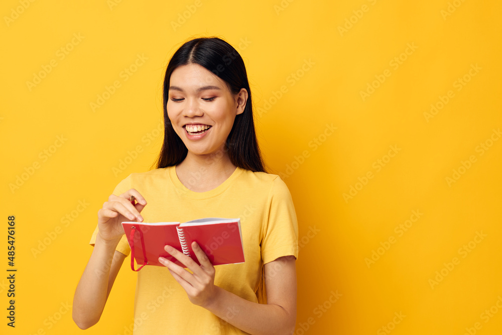 woman with Asian appearance in a yellow t-shirt red notebook training yellow background unaltered woman with Asian appearance in a yellow t-shirt red notebook training yellow background unaltered