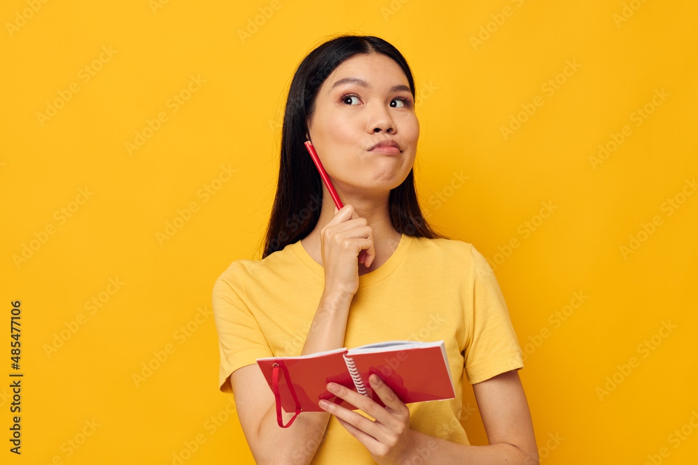 woman with Asian appearance in a yellow t-shirt red notebook training yellow background unaltered woman with Asian appearance in a yellow t-shirt red notebook training yellow background unaltered