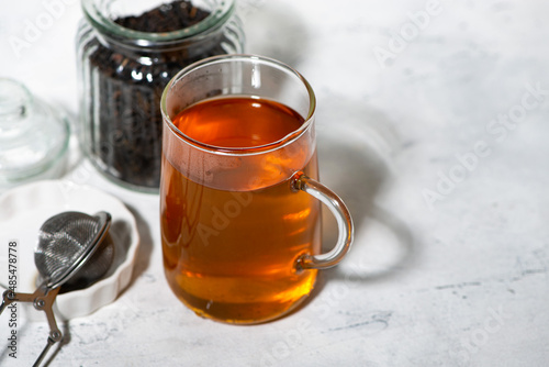 black tea in a glass cup and ingredients for brewing, closeup top view