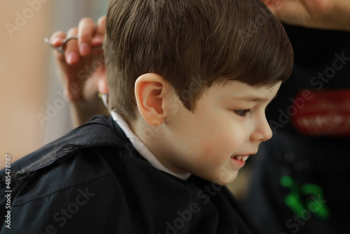 Handsome boy getting his hair and beard cut at barber shop, barber shop rear view