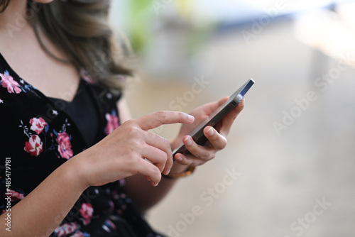 Cropped image of young woman checking social media on her smart phone.