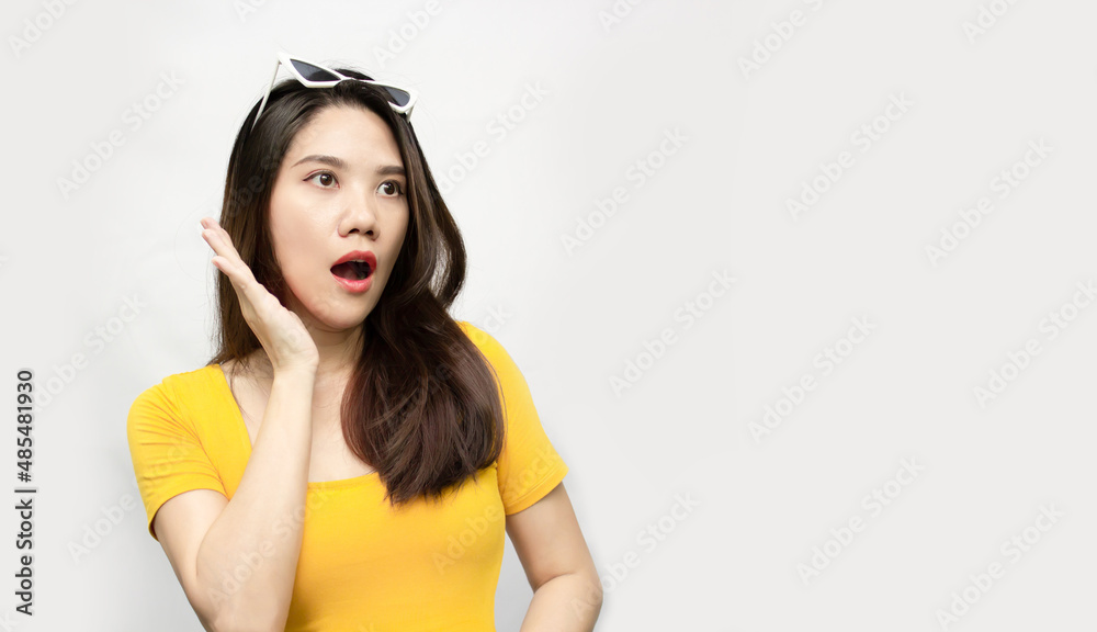 Asian beautiful woman wear yellow T-shirt and wearing white glasses are shocked and surprised with raise both hand beside face and open mouth Asian beautiful woman wear yellow T-shirt and wearing white glasses are shocked and surprised with raise both hand beside face and open mouth