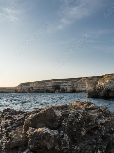 Landscape on the sea. Rocky coast. Mountain cliffs opposite with an arch for the passage of boats. Hole in the rock. No people, Vertical. © Anastasiia