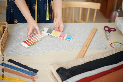 Hands of dressmaker using color palette when choosing lining color for clothing item