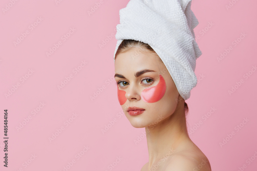 young woman pink patches on the face with a towel on the head isolated background young woman pink patches on the face with a towel on the head isolated background