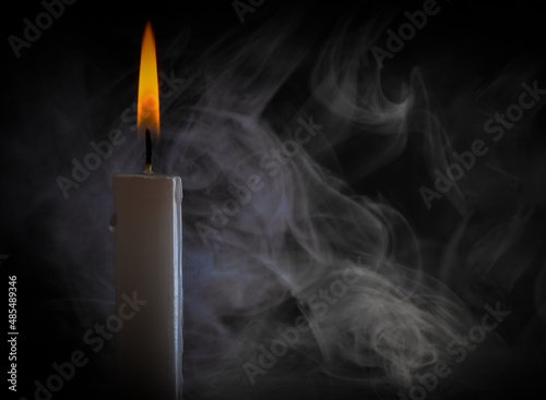a candle burns brightly against a background of smoke. smoke brush. candle fire on a dark background.