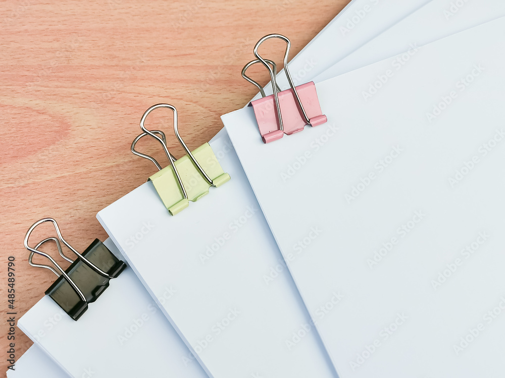 Image of binder clips with blank white paper on wooden table. Image of binder clips with blank white paper on wooden table.