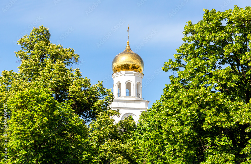 Golden dome of an orthodox church among the trees of the city park