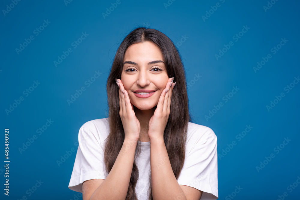 Portrait of happy and attractive caucasian or arab brunette girl in white t-shirt isolated on blue studio background. Portrait of happy and attractive caucasian or arab brunette girl in white t-shirt isolated on blue studio background.