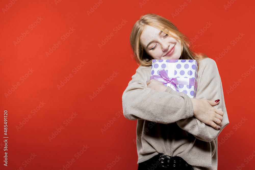 Cute blonde hugs her new year's gift. Birthday. Christmas. Surprise.