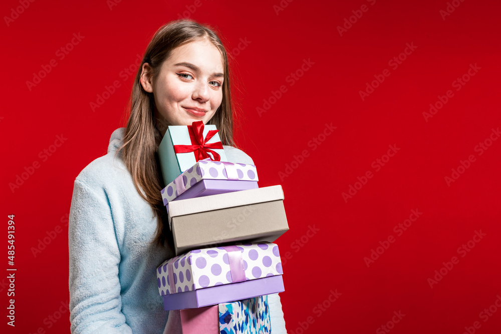 New year. Presentations. A happy blonde stands holding many beautiful boxes in her hands. Birthday. Surprise. The girl is delighted. Christmas presents New year. Presentations. A happy blonde stands holding many beautiful boxes in her hands. Birthday. Surprise. The girl is delighted. Christmas presents