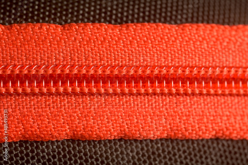 A macro photograph of a closed red Zipper.