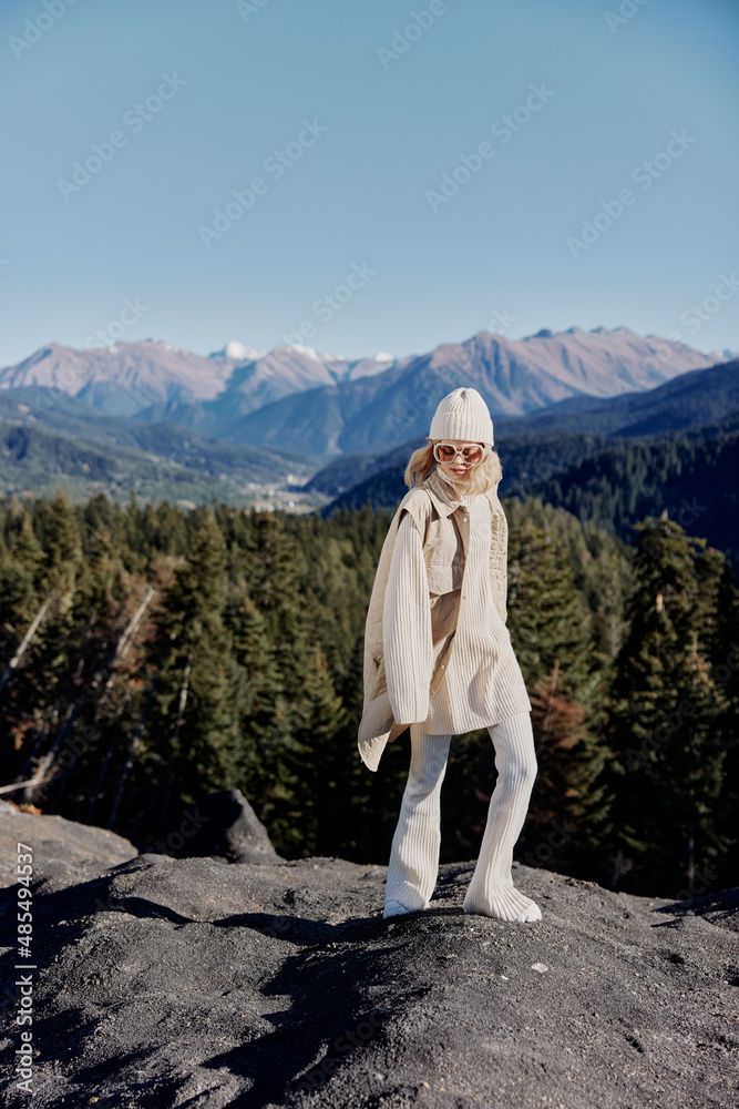 tourist in autumn clothes stands on a rock blue sky lifestyle