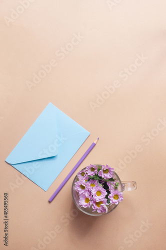 Blue pastel envelope on light yellow background with flowers message invitation concepts photo