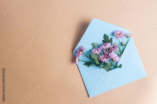 Blue pastel envelope on light yellow background with flowers message invitation concepts photo