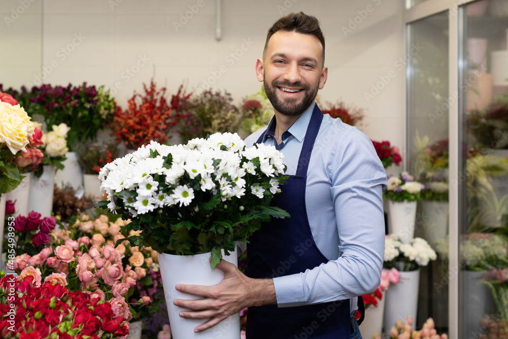 a cheerful florist with a bouquet in his hands against the background of a refrigerator with flowers a cheerful florist with a bouquet in his hands against the background of a refrigerator with flowers