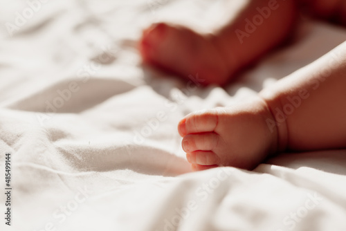 closeup of the bare feet of a newborn baby lying on a white sheet. High quality photo